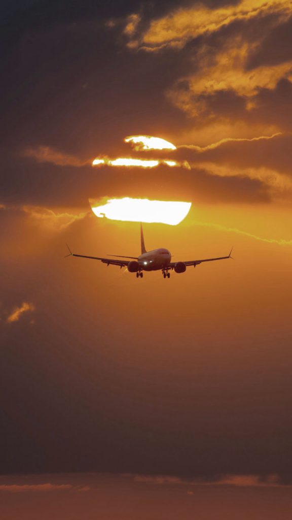 Plane flying in front of the sunset